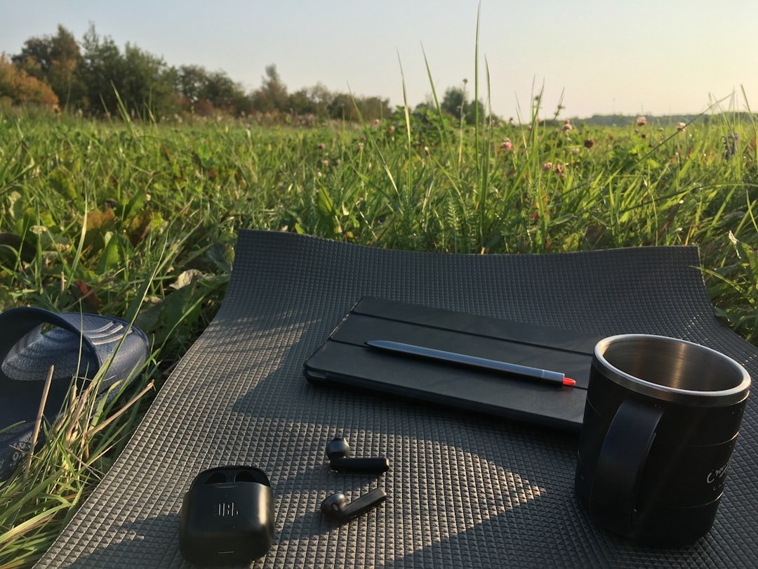 a cup of coffee and a pair of headphones on a mat in a field